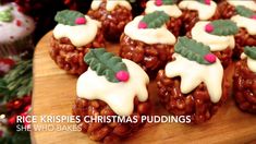 christmas puddings with white frosting and green leaves on top are arranged on a wooden surface