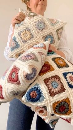 a woman holding a crocheted granny granny blanket and pillow in front of her face