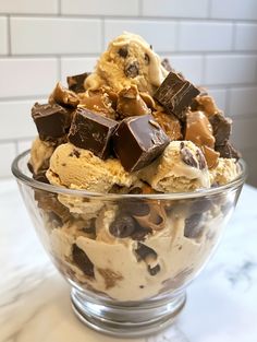 an ice cream sundae with chocolate chunks and cookies in a glass bowl on a marble countertop