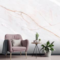 a chair next to a table with a potted plant on it in front of a marble wall