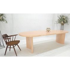 a wooden table and two chairs in front of a white wall with flowers on it