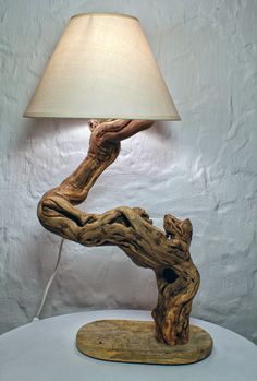 a table lamp made out of driftwood with a white shade on the top and bottom