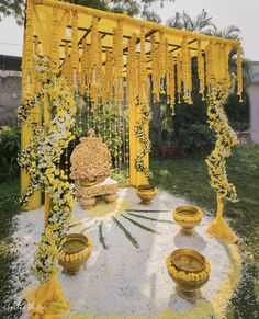 an outdoor ceremony with yellow and white flowers on the ground, surrounded by potted plants