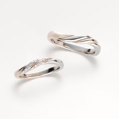 two silver rings with diamond accents on each one, set against a plain white background