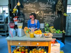 a woman standing behind a counter filled with fruit