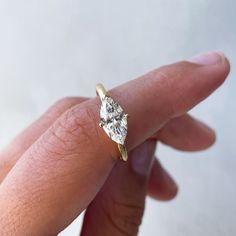 a person's hand holding a diamond ring