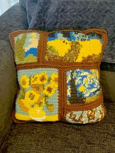 a crocheted patchwork pillow sitting on top of a couch