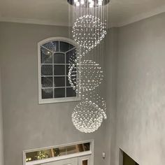 a chandelier hanging from the ceiling in a room with gray walls and white trim