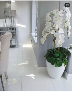 a white vase filled with flowers next to a dining room table