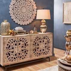 a living room with blue walls and gold accents on the sideboard is shown in this image