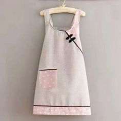 a white dress hanging on a wall next to a wooden hanger with a pink flower