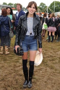 a young woman is standing in the mud with her hat and jacket over her shoulders