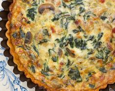 a quiche with spinach, cheese and other toppings in a pie dish