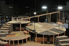 several tables and benches made out of wood in a room with lights on the ceiling