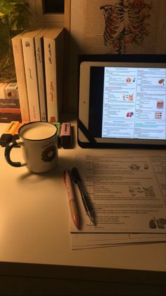 a tablet computer sitting on top of a desk next to a cup and pen in front of it