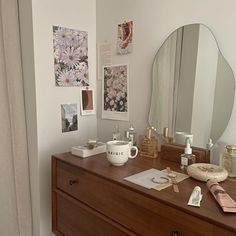 a dresser with a mirror, bowl and other items on it next to a window