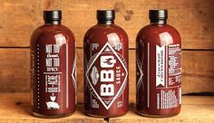 three bottles of bbq sauce sitting on top of a wooden table