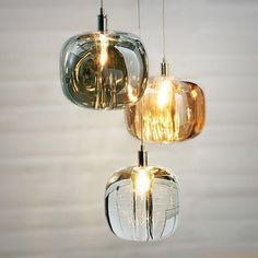 three glass pendant lights hanging from a ceiling