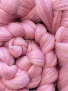 pink colored yarn is piled up in a circular pattern on top of each other, as if it were spinning or spinning