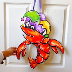 a hand is holding up a paper cutout of a crab on the front door