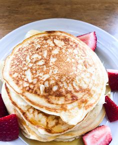 pancakes with syrup and strawberries on a white plate