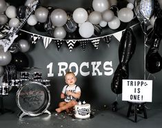 a baby boy sitting in front of a birthday cake