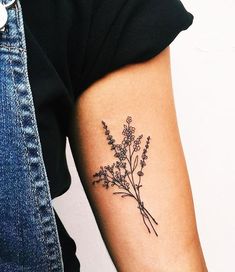 a person with a tattoo on their arm holding a flower in one hand and a plant in the other