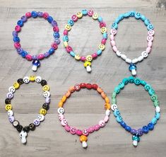 four bracelets with different colored buttons and beads on wooden surface, all decorated in various designs