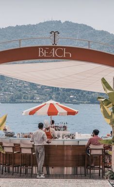 people are sitting at an outdoor bar overlooking the water