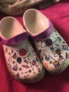 a pair of children's shoes sitting on top of a pink bed spreader