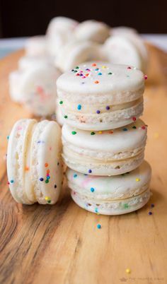 a stack of white frosted donuts with sprinkles on a wooden table