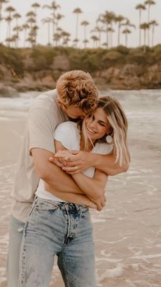 a man and woman hugging on the beach with palm trees in the backgroud