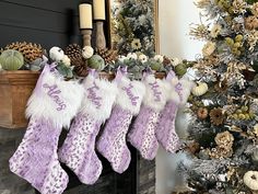 christmas stockings hanging from a mantel decorated with pine cones and greenery