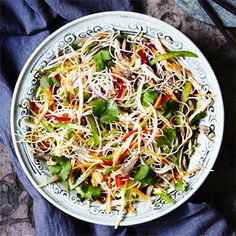 a white bowl filled with lots of veggies and sprouts on top of a blue cloth