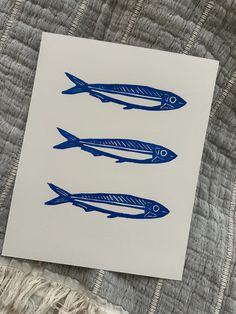 two blue fish on white paper sitting on top of a bed