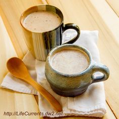 two mugs of hot chocolate sitting on top of a napkin next to each other