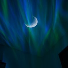 the moon is shining brightly in the night sky with green and blue streaks on it