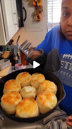 a woman sitting in front of a pan filled with biscuits on top of a table