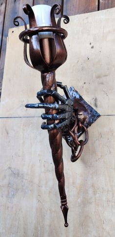 a metal sculpture with an arm holding a cup