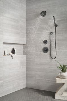 a shower head and hand shower in a white tiled bathroom with grey tile flooring