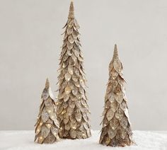 three small christmas trees sitting on top of a snow covered ground next to each other