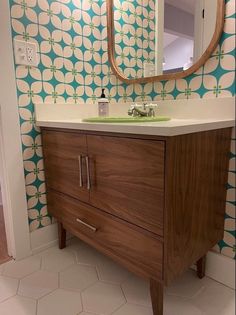 a bathroom with a sink, mirror and wallpaper in the background that looks like circles