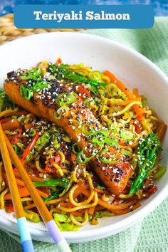 a white bowl filled with noodles and salmon on top of a table next to chopsticks