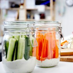 carrots, celery, and cucumbers in jars on a counter