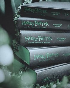 a stack of harry potter books sitting on top of each other in front of green leaves