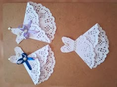 three pieces of paper with bows and lace on them sitting on top of a table