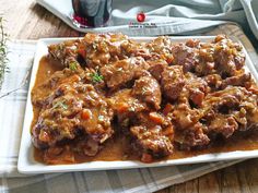 a white plate topped with meat covered in gravy