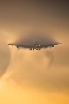 an airplane is flying through the clouds at sunset