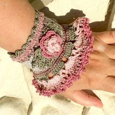 a close up of a person wearing a crocheted bracelet with flowers on it