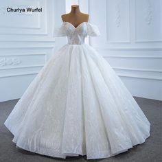 a white ball gown on a mannequin head stand in front of a wall